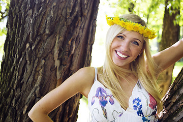 Image showing happy blond young woman in park smiling, floral close up