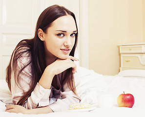 Image showing young pretty brunette woman laying in bed, luxury white interior