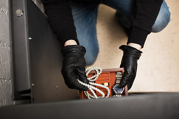 Image showing thief stealing valuables from safe at crime scene