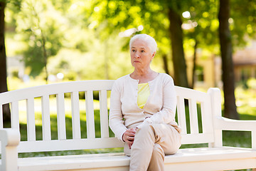 Image showing sad senior woman sitting on bench at summer park