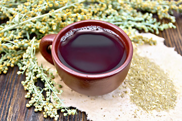 Image showing Tea with wormwood in brown cup on dark board