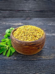 Image showing Fenugreek with leaf in clay bowl on black wooden board