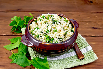 Image showing Couscous with spinach and green peas in bowl on board