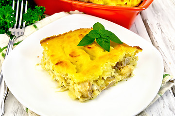 Image showing Gratin potato with fish in plate on light board