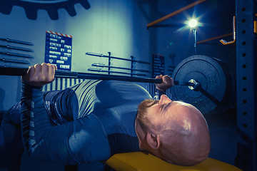 Image showing Portrait of super fit muscular young man working out in gym with barbell