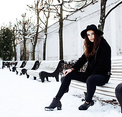 Image showing young pretty teenage hipster girl outdoor in winter snow park having fun drinking coffee, warming up happy smiling, lifestyle people concept