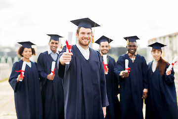 Image showing happy students in mortar boards with diplomas