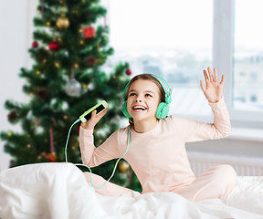 Image showing girl with smartphone and headphones at christmas