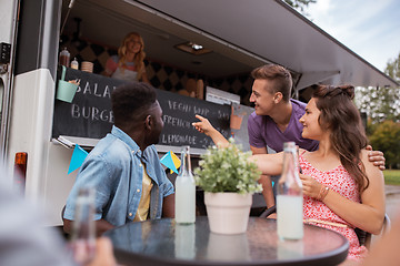 Image showing friends with drinks sitting at table at food truck