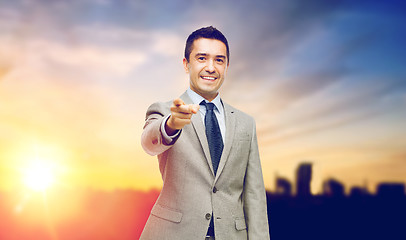 Image showing smiling businessman pointing at you over city