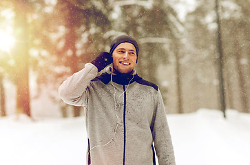 Image showing happy sports man with earphones in winter forest