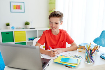 Image showing student boy with laptop writing to notebook