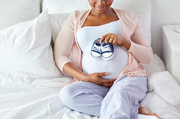 Image showing pregnant african woman with baby bootees in bed