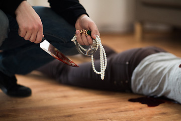 Image showing criminal with knife and jewelry at crime scene