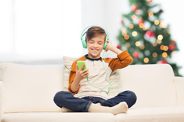 Image showing boy with smartphone and headphones at christmas