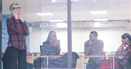 Image showing Business Woman Looking Through A Window And using On A Cell Phon