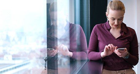 Image showing Elegant Woman Using Mobile Phone by window in office building