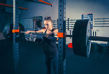 Image showing Fit young woman lifting barbells looking focused, working out in a gym