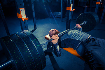 Image showing Portrait of super fit muscular young man working out in gym with barbell