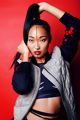 Image showing young pretty asian girl posing cheerful on red background, fashion style makeup and hair, lifestyle modern orient people concept