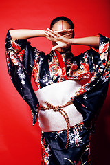 Image showing young pretty geisha on red background posing in kimono, oriental people concept close up