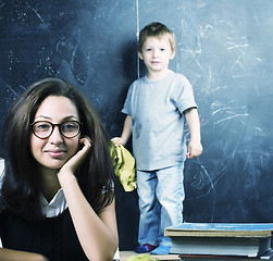 Image showing little cute boy in glasses with young real teacher, classroom studying