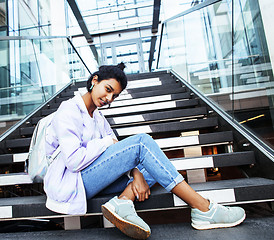 Image showing young cute modern indian girl at university building sitting on stairs reading a book, wearing hipster glasses, lifestyle people concept