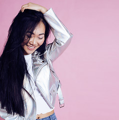 Image showing young pretty smiling asian korean girl wearing modern fashion clothers on pink background, lifestyle people concept 