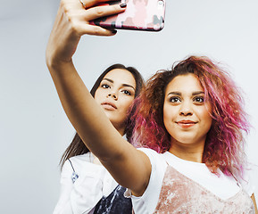 Image showing lifestyle people concept: two pretty stylish modern hipster teen girl having fun together, diverse nation mixed races, happy smiling making selfie