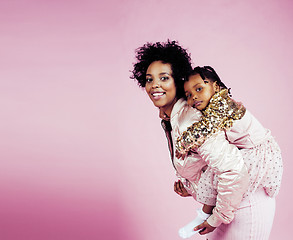 Image showing young pretty african-american mother with little cute daughter hugging, happy smiling on pink background, lifestyle modern people concept