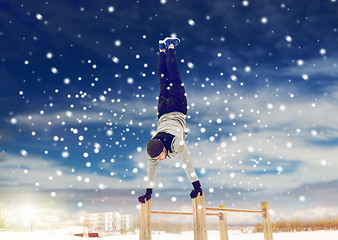 Image showing young man exercising on parallel bars in winter