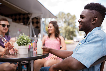 Image showing friends with drinks sitting at table at food truck