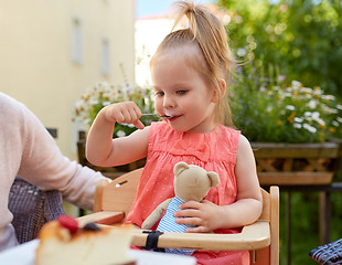 Image showing little girl with spoon eating outdoors