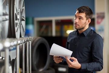 Image showing auto business owner and wheel rims at car service