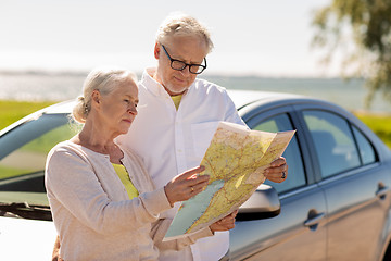 Image showing senior couple with car looking for location on map