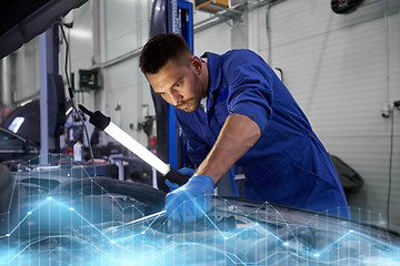 Image showing mechanic man with lamp repairing car at workshop