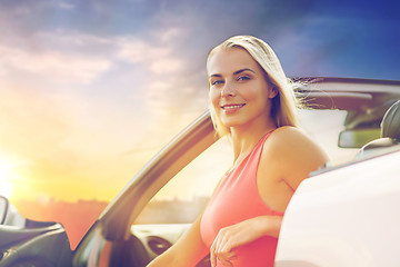 Image showing happy woman in convertible car over evening sky