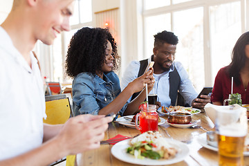 Image showing happy friends with smartphones at restaurant