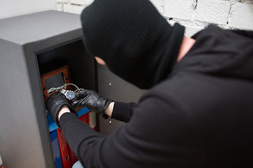 Image showing thief stealing valuables from safe at crime scene