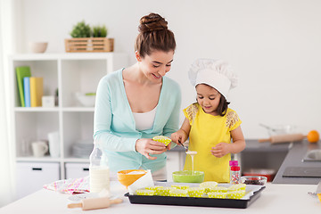 Image showing happy mother and daughter baking cupcakes at home