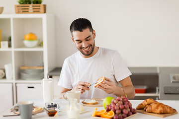 Image showing man eating toast with coffee at home kitchen