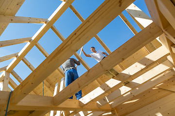 Image showing Builders at work with wooden roof construction.