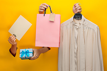 Image showing Female hand holding bright shopping bag and gifts