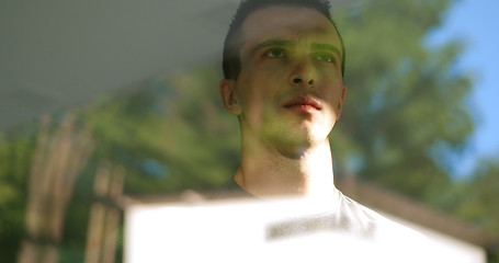 Image showing reflection of sad man looking through window