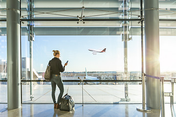 Image showing Young woman waiting at airport, looking through the gate window.