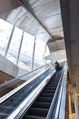 Image showing Businesswoman with large black bag and mobile phone ascending on escalator.