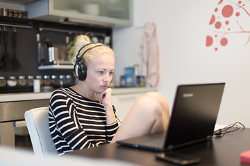 Image showing Adult woman in her casual home clothing working and studying remotely from her small flat late at night.