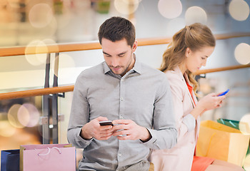 Image showing couple with smartphones and shopping bags in mall