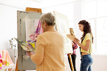 Image showing senior woman painting at art school studio