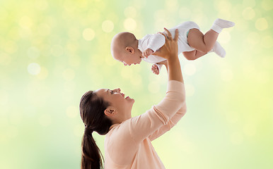 Image showing happy mother playing with little baby over green